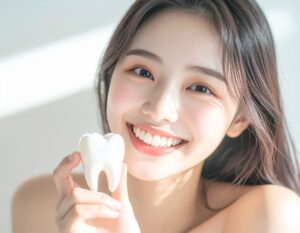 真っ白な歯の模型を手に持った笑顔の女性